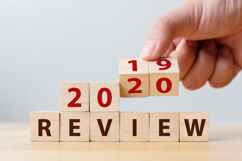 2020 review concept. Hand flip wood cube change year 2019 to 2020 and the word REVIEW on wooden block on wood table