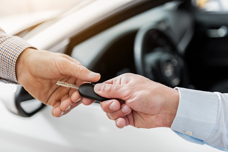 Person receiving car keys from a car salesman