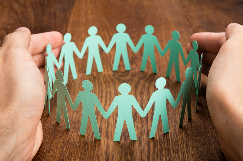Hands protecting group of cardboard cut-out figures