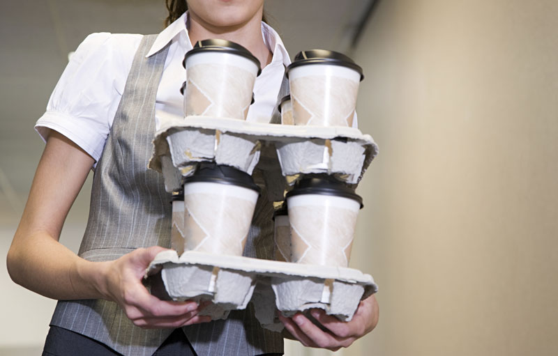 Female intern carrying coffees in a hallway